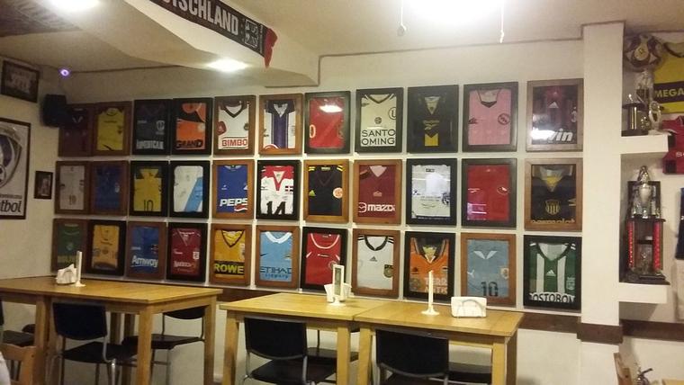 Pared del restaurante cubierta de camisetas de fútbol enmarcadas